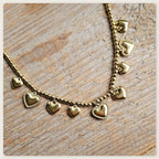 Goudkleurige stainless steel kralenketting met meerdere kleine hartbedels