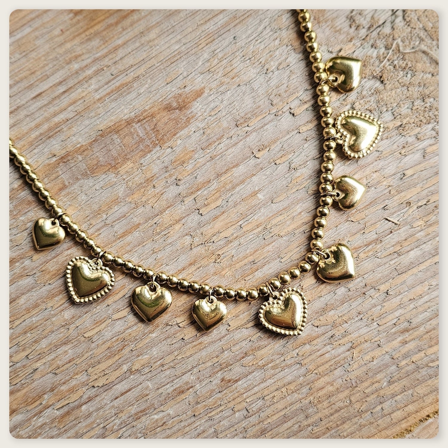 Goudkleurige stainless steel kralenketting met meerdere kleine hartbedels