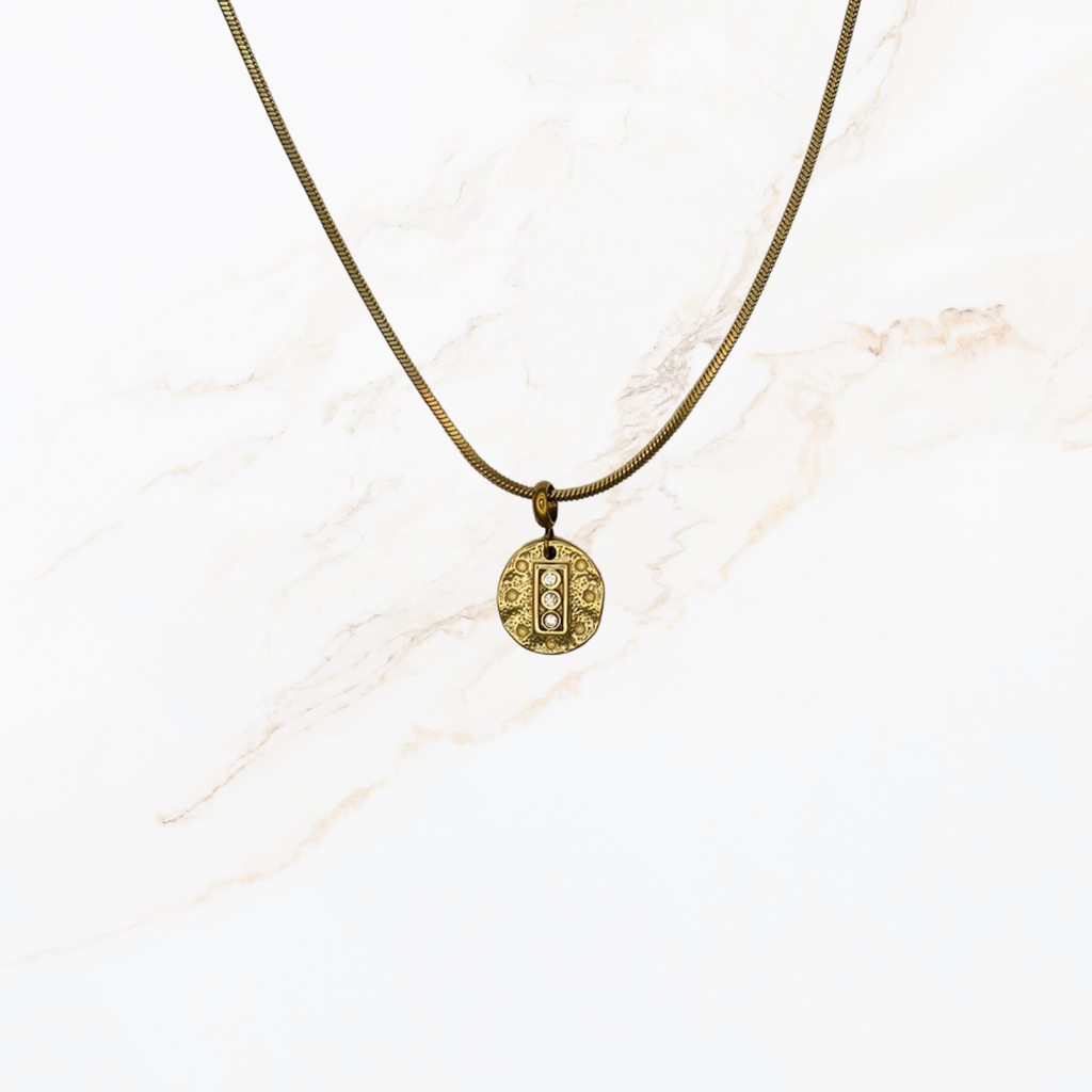Goudkleurige snake chain ketting voor het zelf samenstellen van een ketting met verwisselbare bedels op lichte marmer achtergrond.
