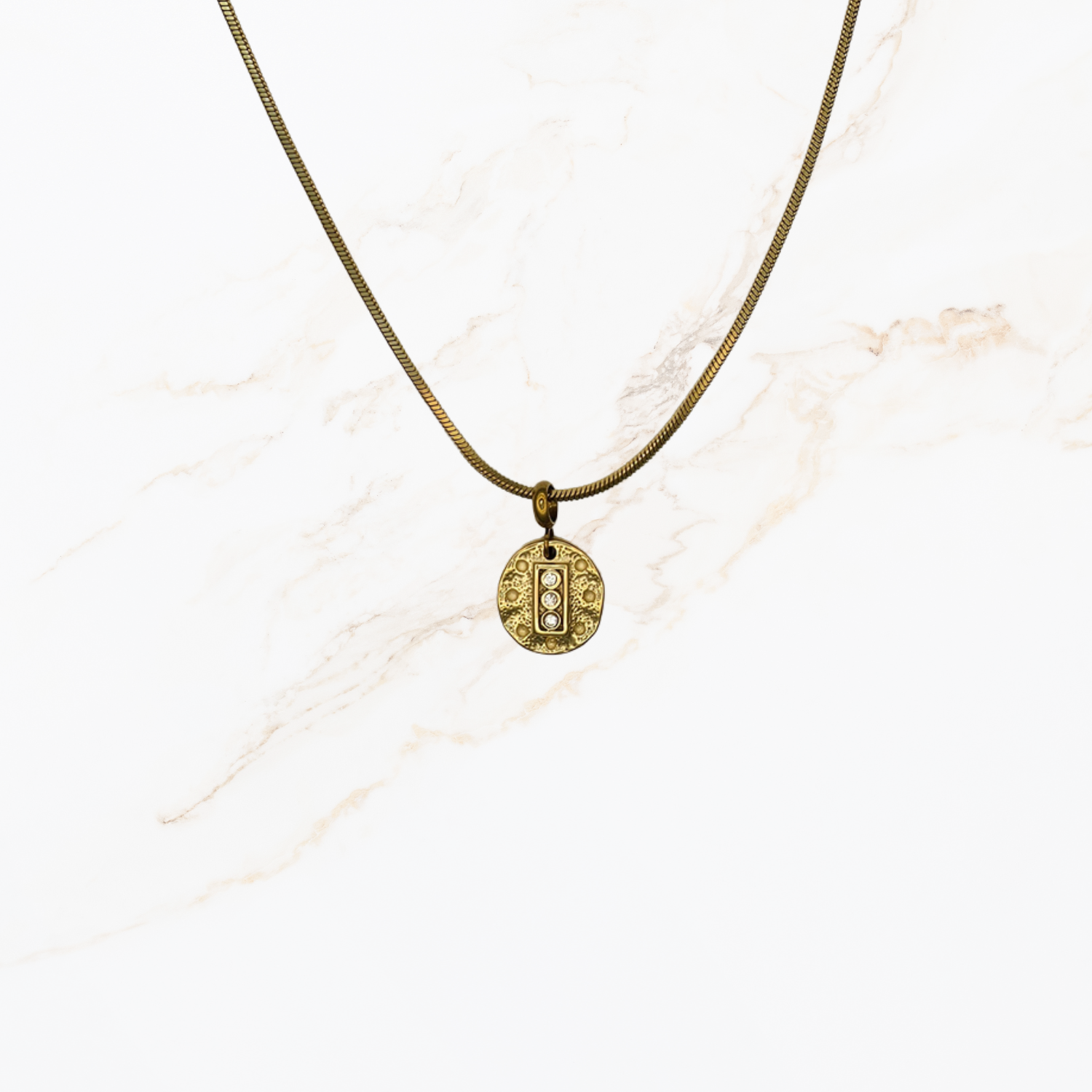 Goudkleurige snake chain ketting voor het zelf samenstellen van een ketting met verwisselbare bedels op lichte marmer achtergrond.