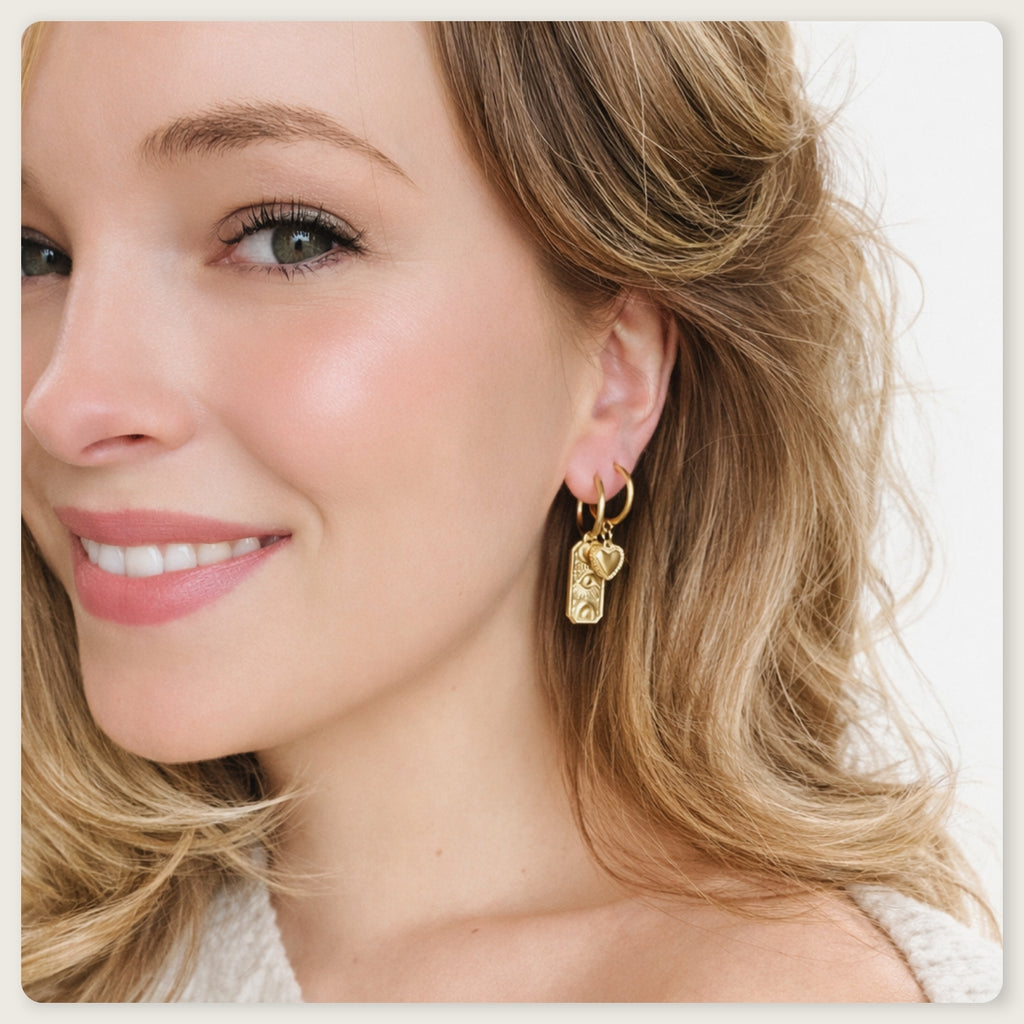 Seyso goudkleurige ring oorbellen met klein hartvormig hangertje op lichte marmerlook achtergrond