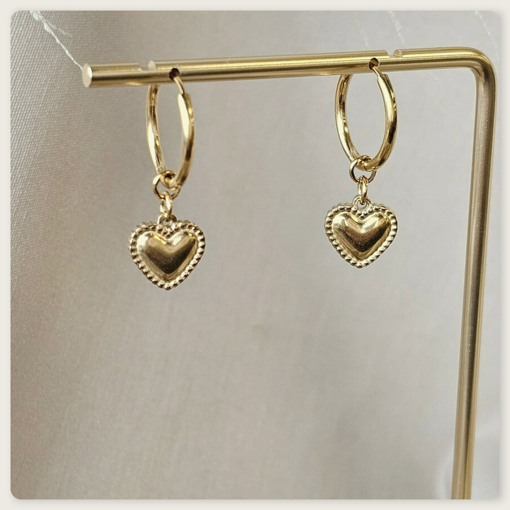 Seyso goudkleurige ring oorbellen met klein hartvormig hangertje op lichte marmerlook achtergrond