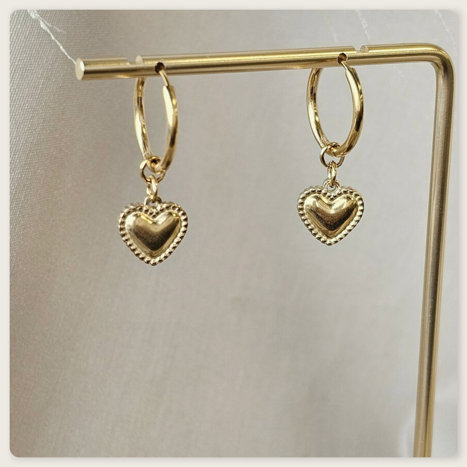Seyso goudkleurige ring oorbellen met klein hartvormig hangertje op lichte marmerlook achtergrond