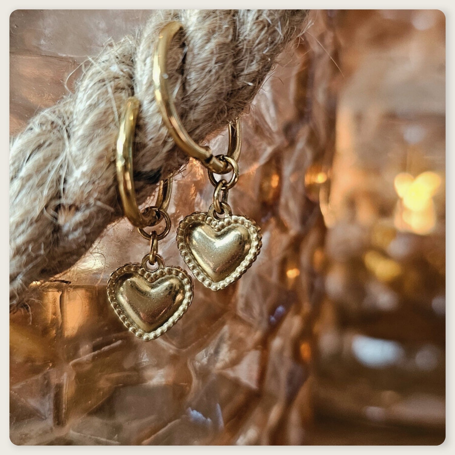 Seyso goudkleurige ring oorbellen met klein hartvormig hangertje op lichte marmerlook achtergrond