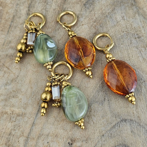Handgemaakte hangoorbellen met amberkleurige en zachtgroene kralen, goudkleurige details en elegante hangers. Trendy dames sieraden voor de herfst.