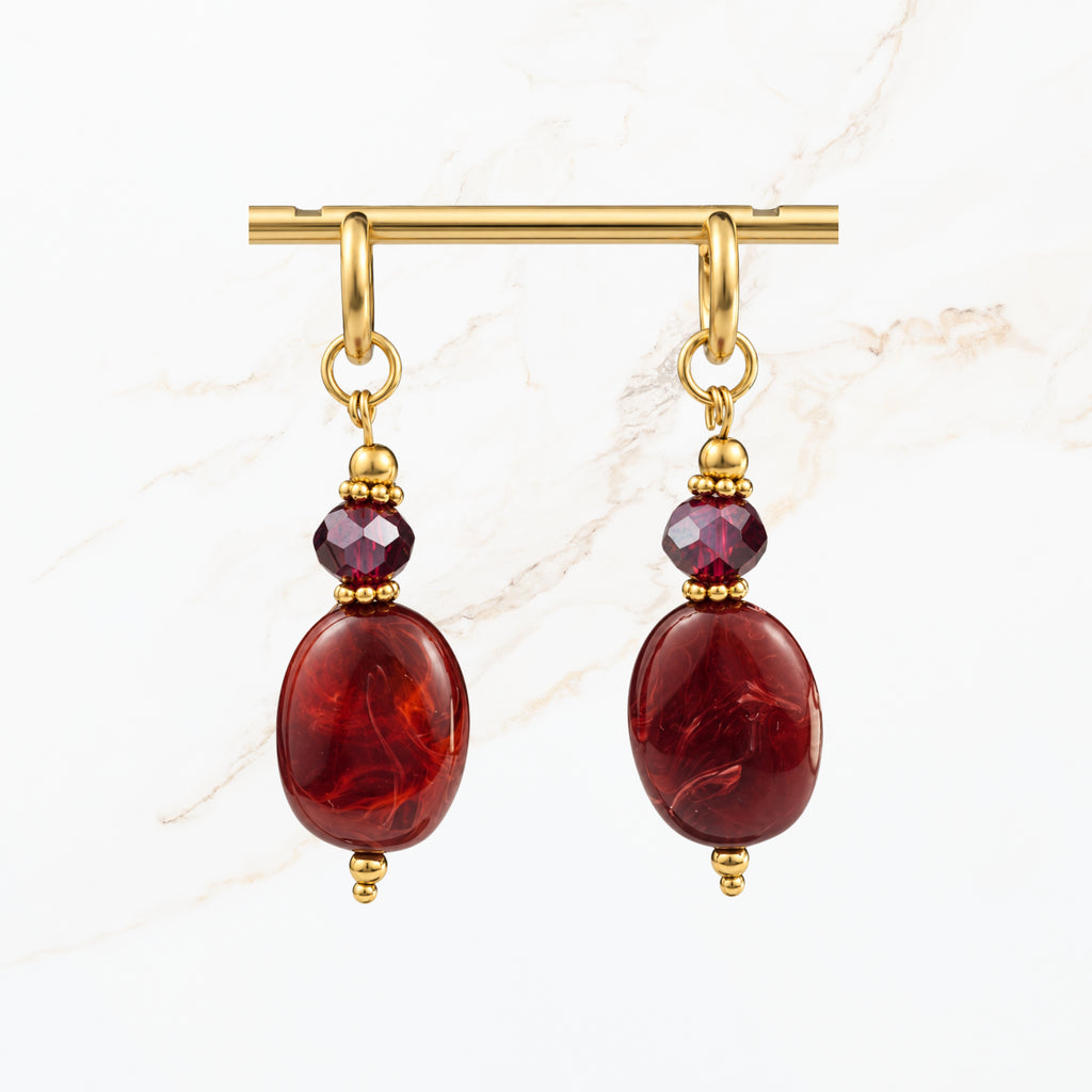 Elegante bordeaux rode oorbellen met glanzende ovale hangers, paarse kristallen en goudkleurige details. Trendy dames sieraden van Seyso.