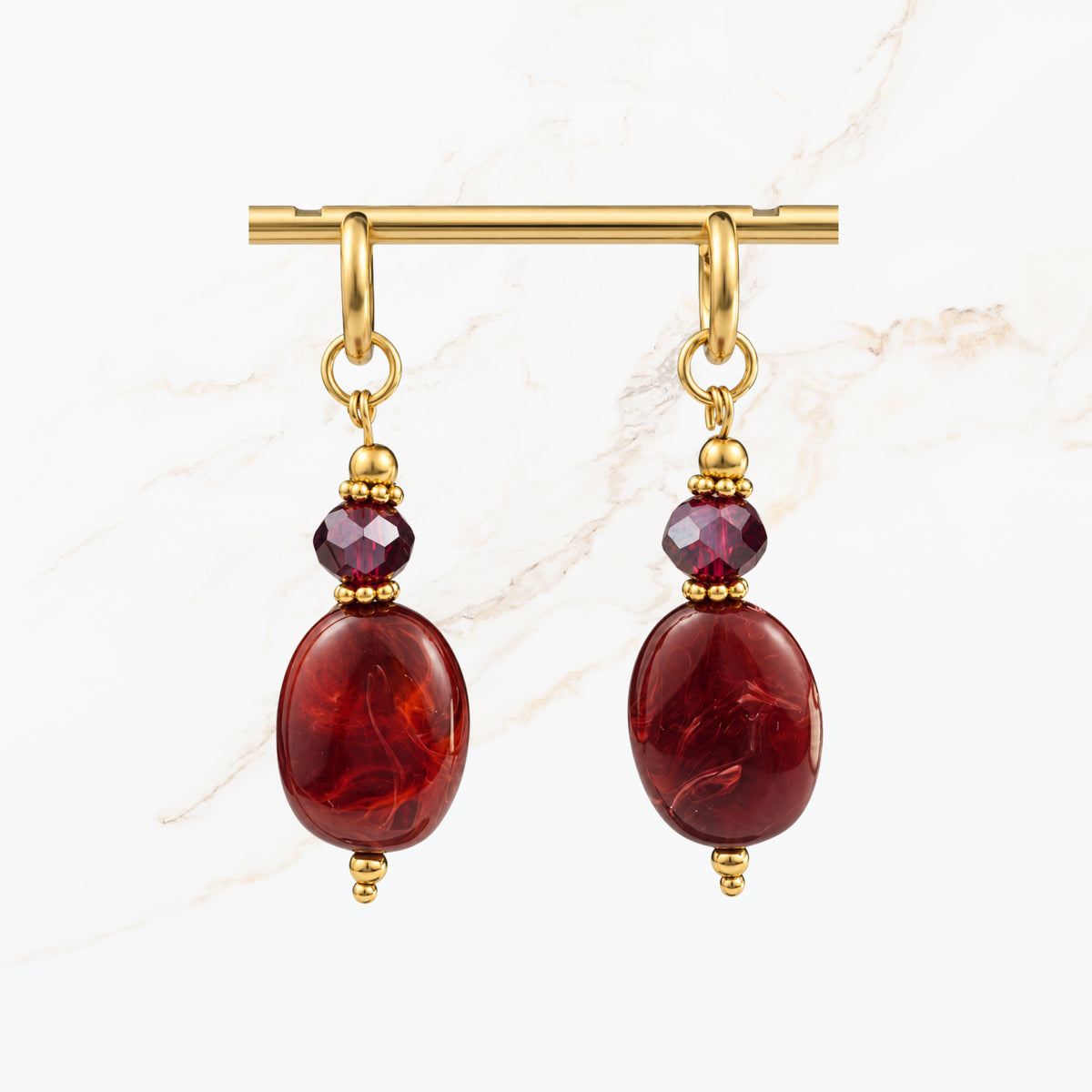 Elegante bordeaux rode oorbellen met glanzende ovale hangers, paarse kristallen en goudkleurige details. Trendy dames sieraden van Seyso.