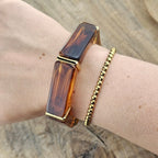 Bruine elastische armband voor dames in warme amberkleur met gouden accenten