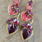 Kleurrijke statement oorbellen met roze en paarse hartvormige hangers, siersteentjes en goudkleurige details uit de Burgundy Bloom collectie.