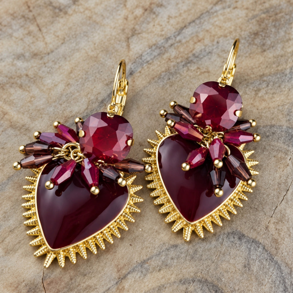 Twee paar hartvormige statement oorbellen in roze en bordeaux rood met kleurrijke kristallen en goudkleurige details uit de Burgundy Bloom collectie van Seyso.