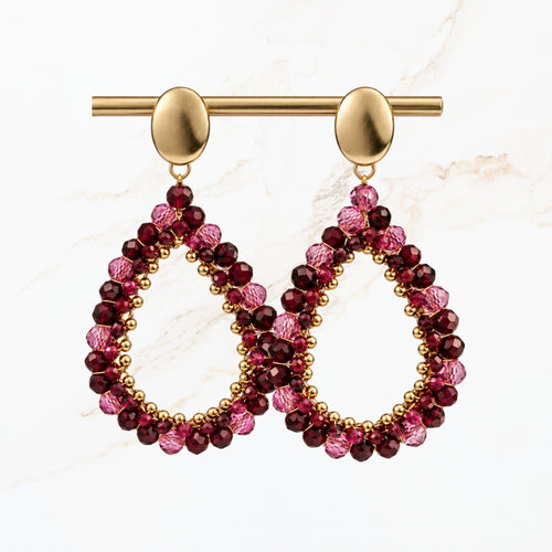 Bordeaux rode druppel oorbellen met fonkelende paarse en rode kralen, goudkleurige ovale oorstekers en open druppelvorm. Elegante sieraden van Seyso.