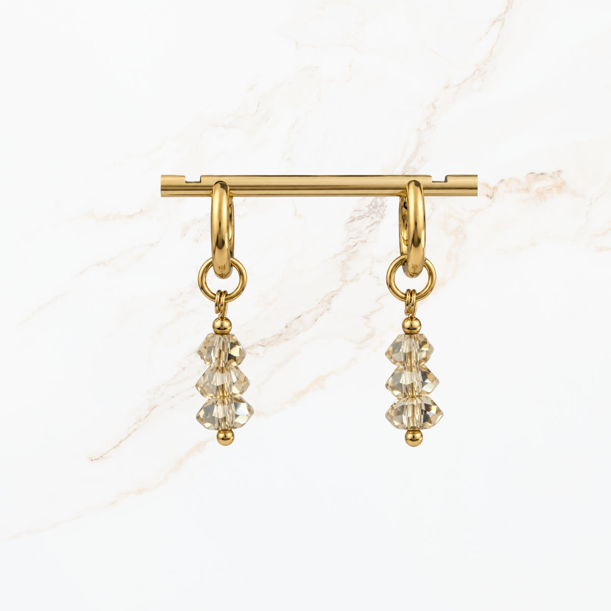 Elegante goudkleurige hangoorbellen met transparante gefacetteerde kristalkralen en subtiele gouden details. Stijlvolle dames oorbellen van Seyso.