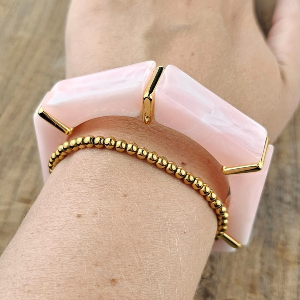Lichtroze statement armband met gouden details gecombineerd met een fijne goudkleurige kralen armband