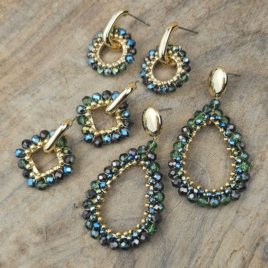 Groene oorbellen in ronde en druppelvormige modellen met fonkelende groene en turquoise kralen en goudkleurige details op een stenen achtergrond.