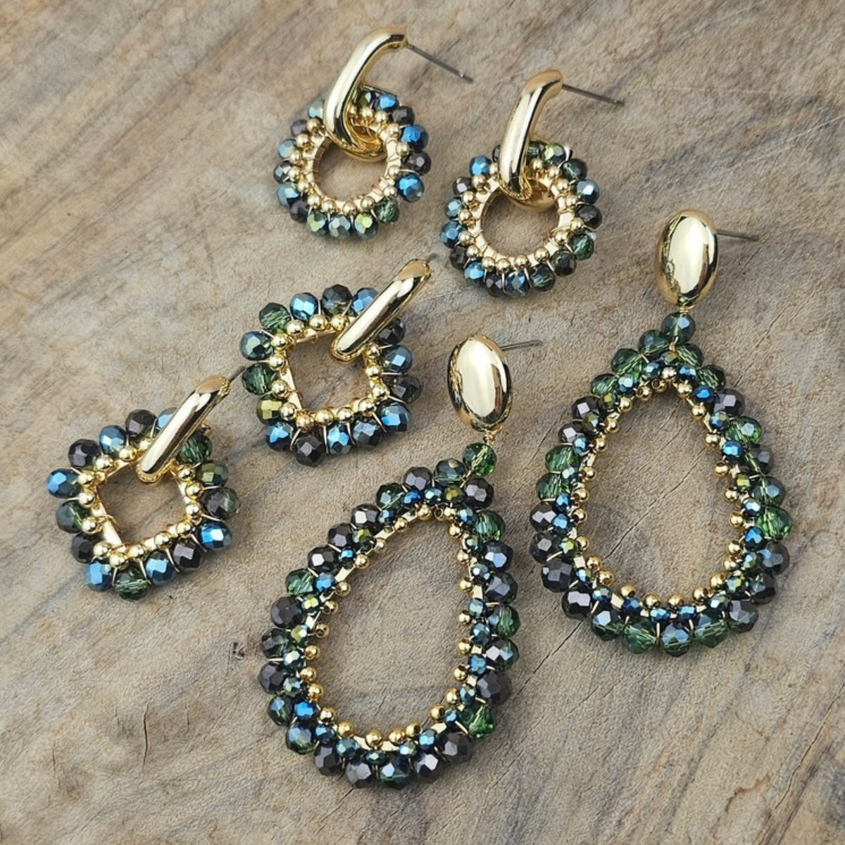 Groene oorbellen in ronde en druppelvormige modellen met fonkelende groene en turquoise kralen en goudkleurige details op een stenen achtergrond.