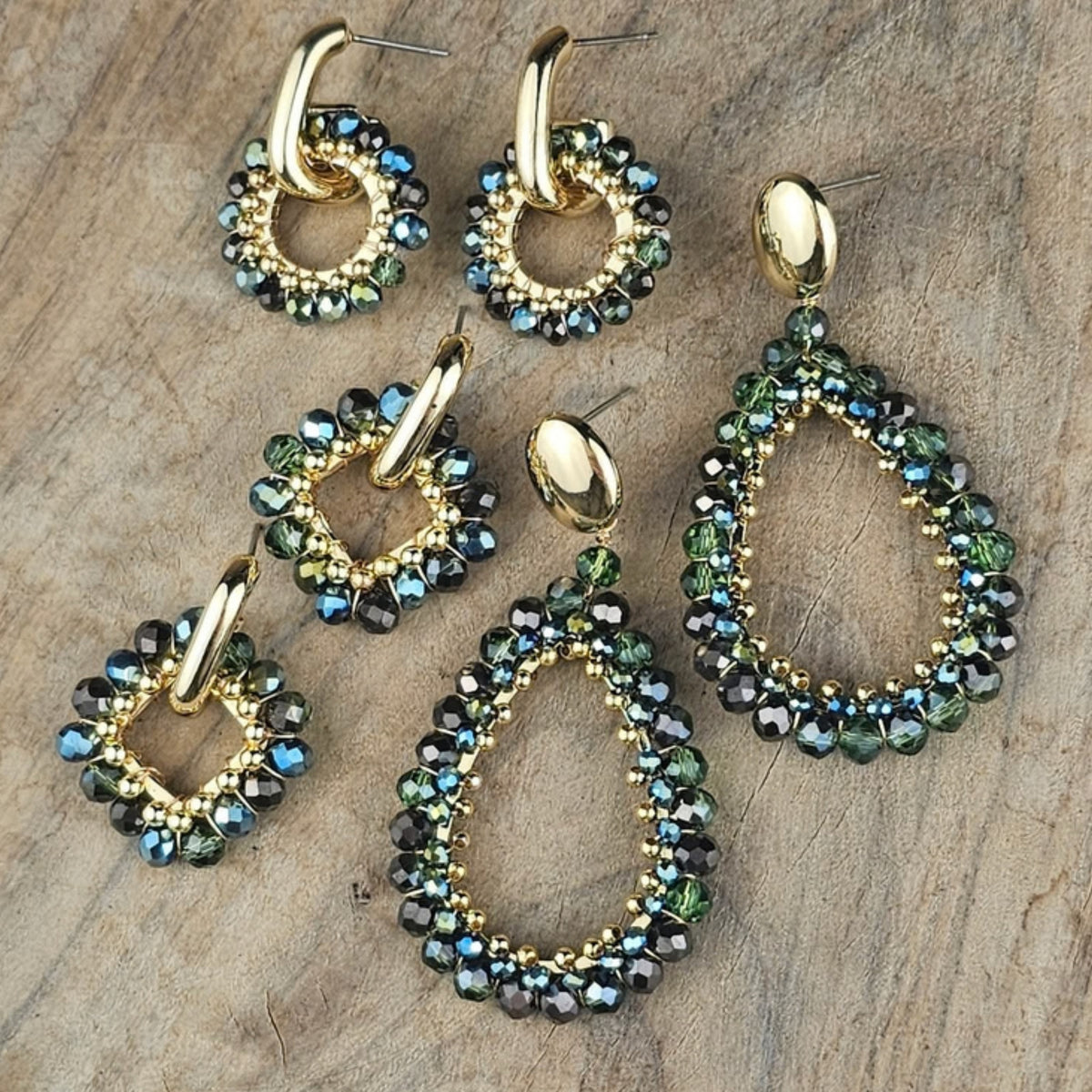 Verschillende groene statement oorbellen met ronde en druppelvormige hangers, glinsterende groenblauwe kralen en goudkleurige details.