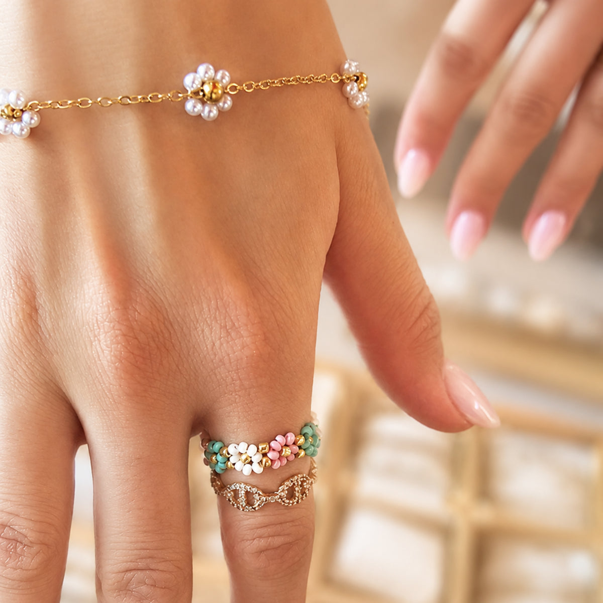 Gouden dames armband met witte bloemetjes gecombineerd met ringen en sieraden