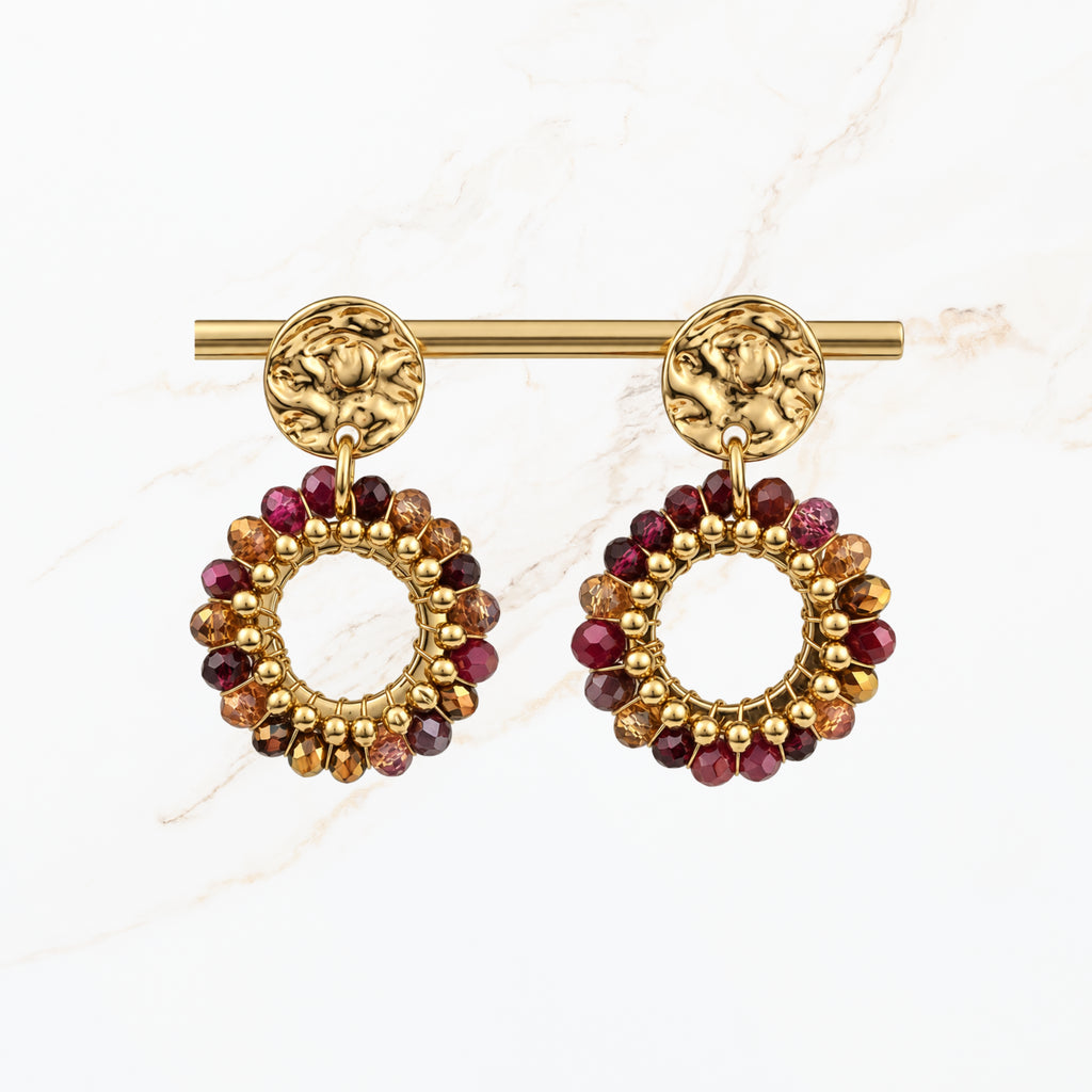 Goudkleurige ronde statement oorbellen met bordeaux rode, paarse en gouden kralen, open cirkelvormige hangers en sierlijke gouden oorstekers van Seyso.