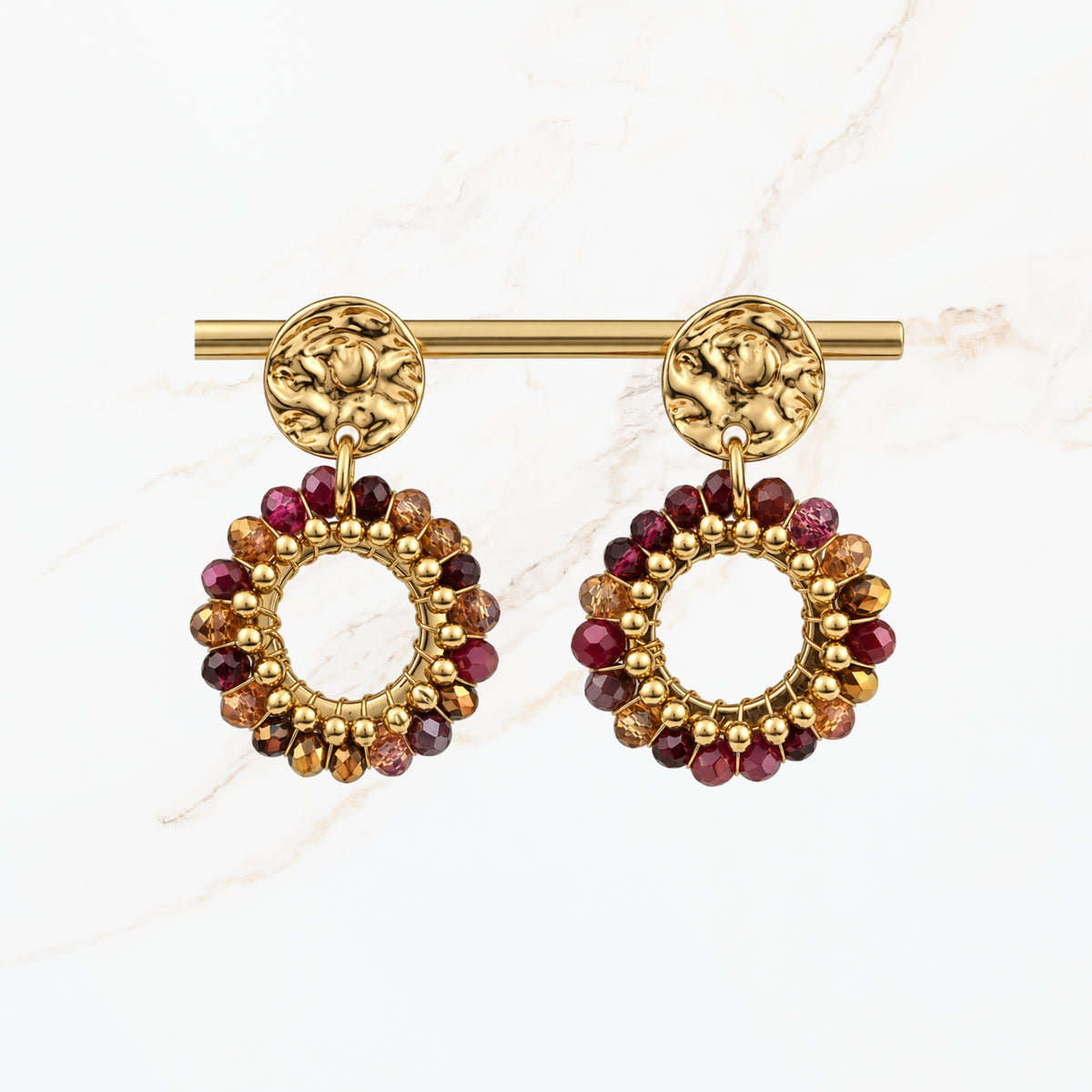 Goudkleurige ronde statement oorbellen met bordeaux rode, paarse en gouden kralen, open cirkelvormige hangers en sierlijke gouden oorstekers van Seyso.
