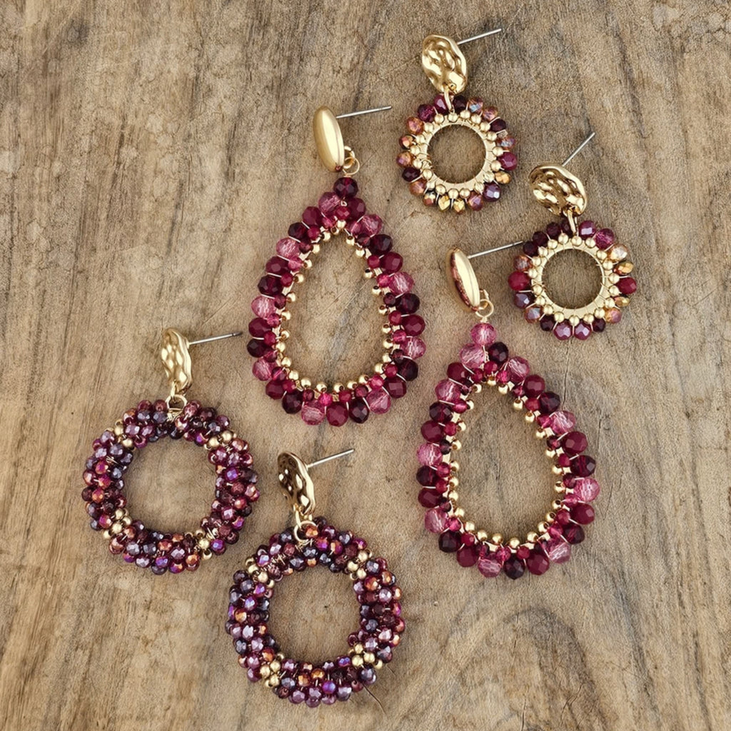 Handgemaakte ronde oorbellen met goudkleurige details en glinsterende kralen in bordeaux rood, paars en goud. Elegante herfst sieraden voor dames.