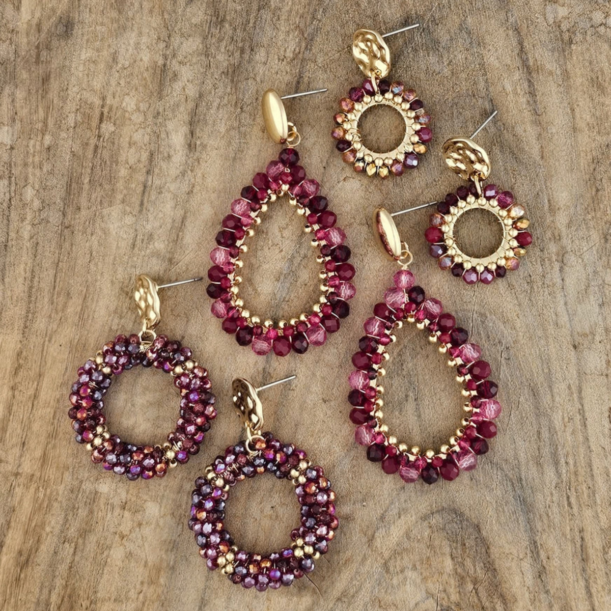 Handgemaakte ronde oorbellen met goudkleurige details en glinsterende kralen in bordeaux rood, paars en goud. Elegante herfst sieraden voor dames.