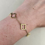 Gouden klaver armband met witte details gedragen om de pols