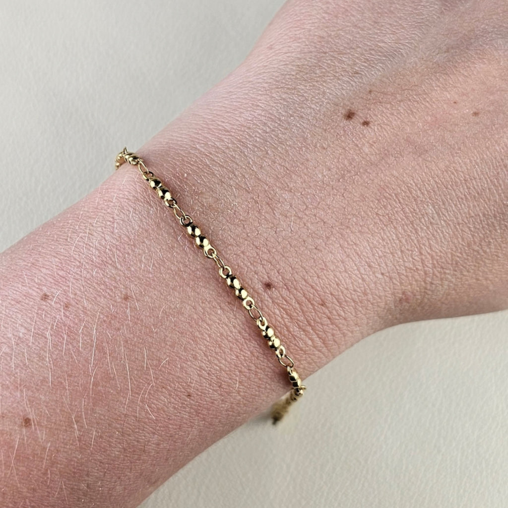 Minimalistische gouden dames armband met kleine ronde kralen om de pols