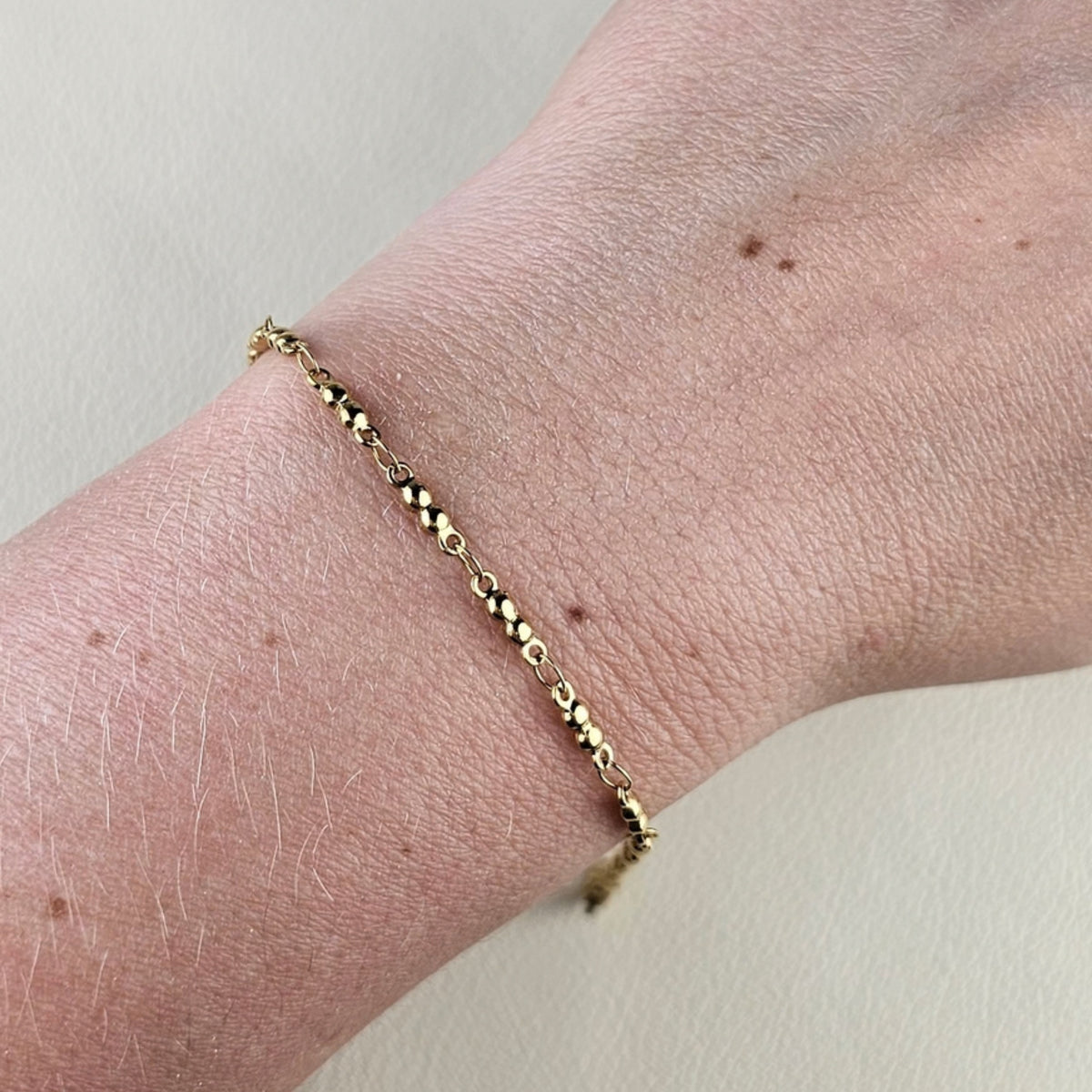 Minimalistische gouden dames armband met kleine ronde kralen om de pols