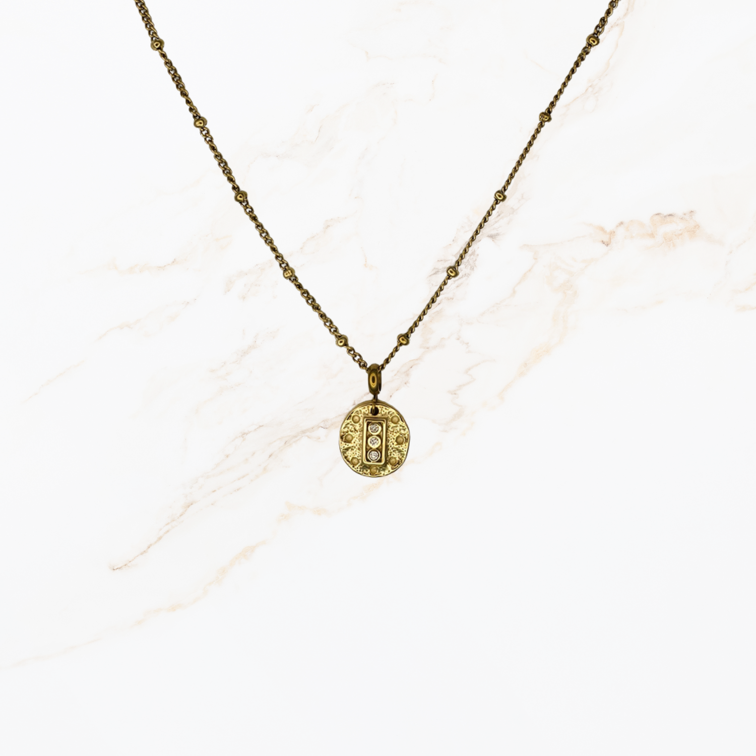 Fijne goudkleurige ketting met kleine bolletjes voor het samenstellen van een persoonlijke ketting met bedels op lichte marmer achtergrond.