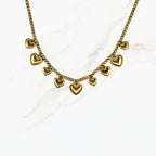 Goudkleurige stainless steel kralenketting met meerdere kleine hartbedels