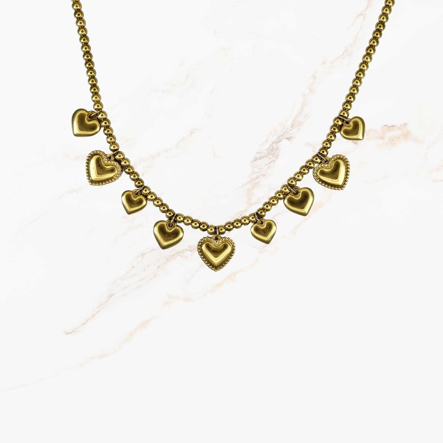 Goudkleurige stainless steel kralenketting met meerdere kleine hartbedels