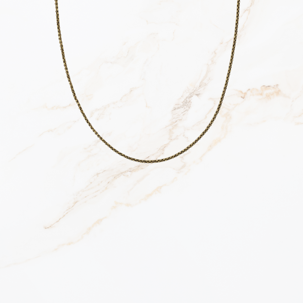 Goudkleurige ketting voor het zelf samenstellen van een ketting met verwisselbare bedels op lichte marmer achtergrond.