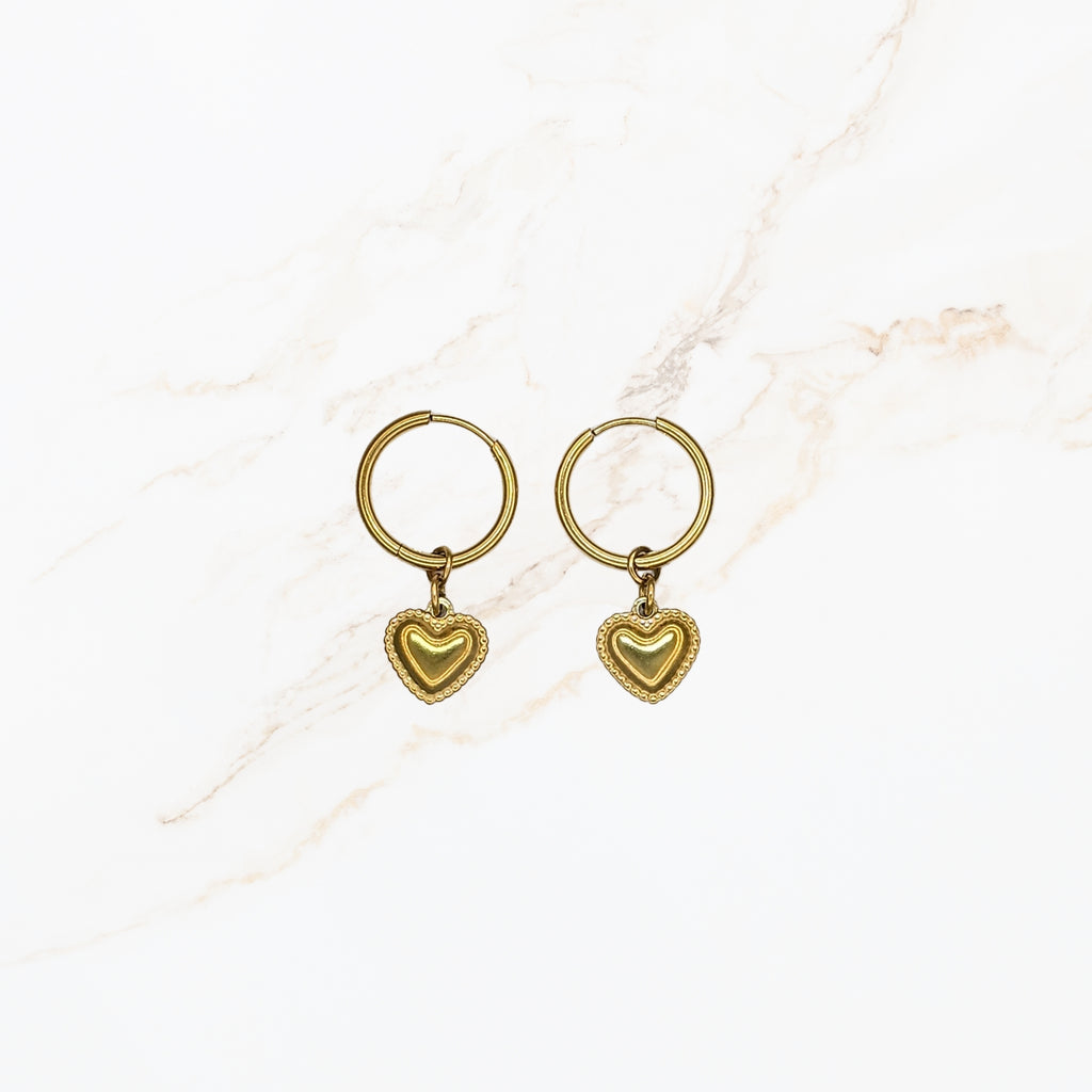 Seyso goudkleurige ring oorbellen met klein hartvormig hangertje op lichte marmerlook achtergrond