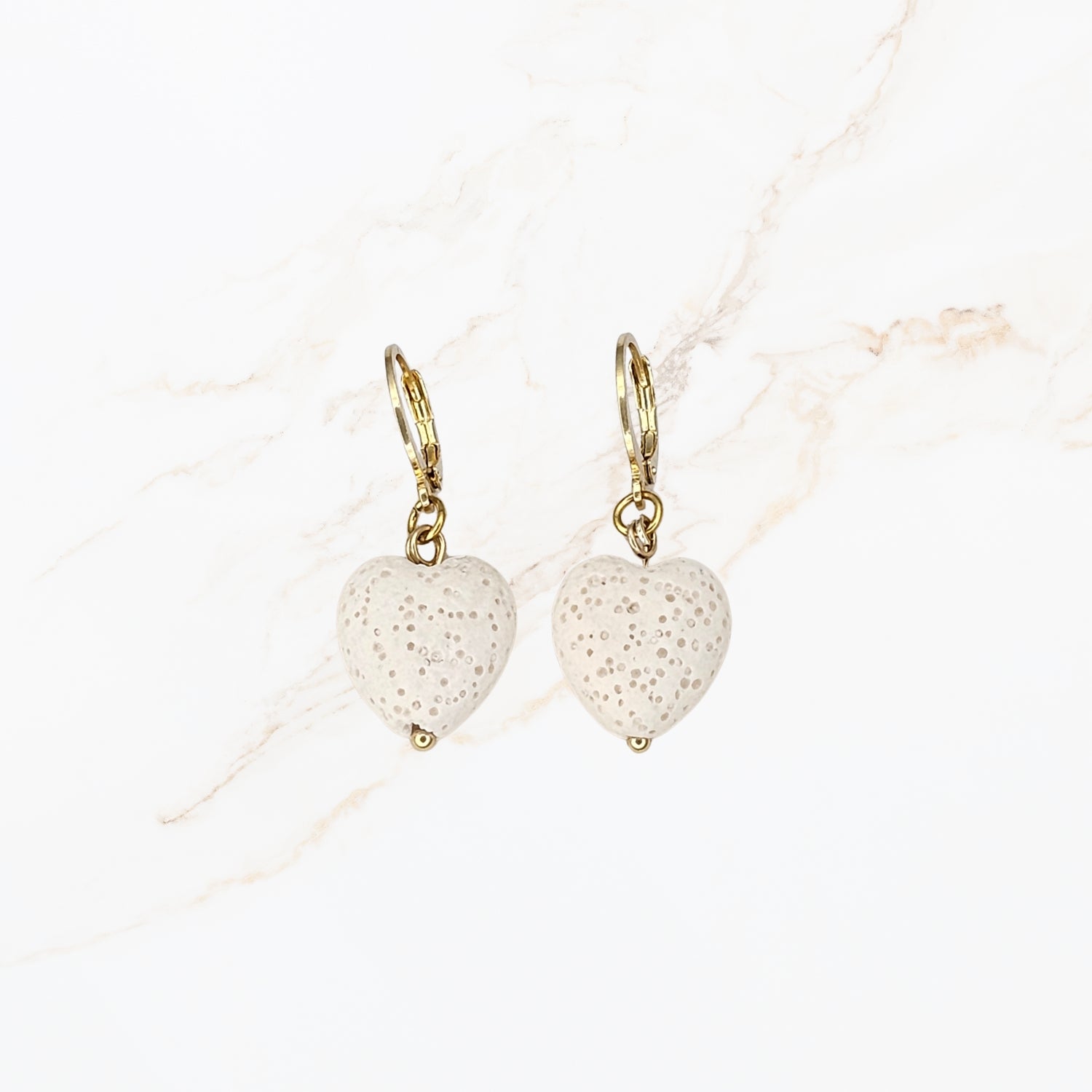 Seyso witte hartvormige lavasteen oorbellen met goudkleurige stainless steel haakjes en natuurlijke structuur in elegant en vrouwelijk design.