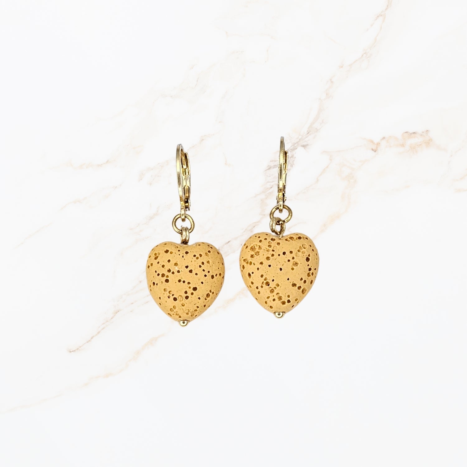 Seyso honinggele hartvormige lavasteen oorbellen met goudkleurige stainless steel haakjes en natuurlijke structuur in warm en vrouwelijk design.