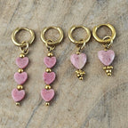 Verschillende lichtroze hartjes oorbellen met goudkleurige oorhaken, uitgevoerd met enkele en meerdere roze hartvormige hangers van Seyso.