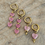 Verschillende modellen roze hartjes hangoorbellen met goudkleurige oorhaken en zachtroze kralen. Vrouwelijke sieraden voor een romantische look.