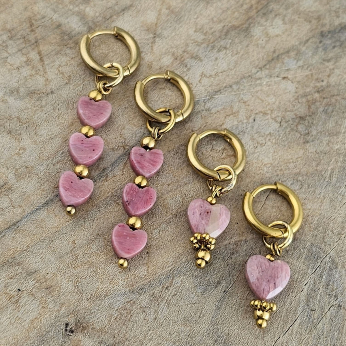 Verschillende modellen roze hartjes hangoorbellen met goudkleurige oorhaken en zachtroze kralen. Vrouwelijke sieraden voor een romantische look.