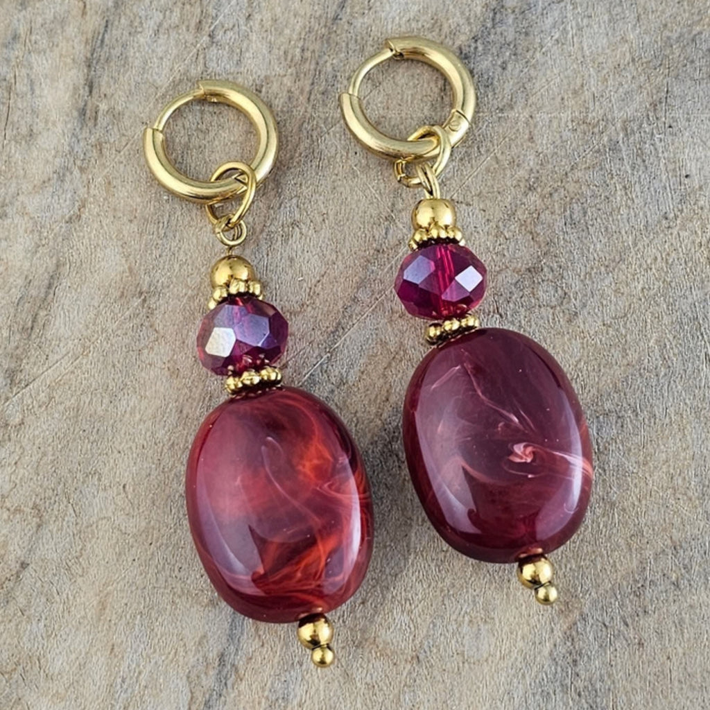 Bordeaux rode hangoorbellen met ovale kralen, fonkelende paarse kristallen en goudkleurige oorhaken. Stijlvolle herfst sieraden van Seyso.