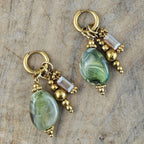 Saliegroene oorbellen met glanzende ovale kralen, sierlijke goudkleurige hangers en transparante accentkralen. Stijlvolle groene oorbellen voor dames.
